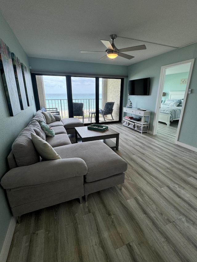 living room featuring hardwood / wood-style flooring, ceiling fan, and a textured ceiling