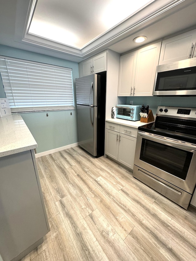 kitchen featuring gray cabinets, light stone countertops, stainless steel appliances, and light hardwood / wood-style floors