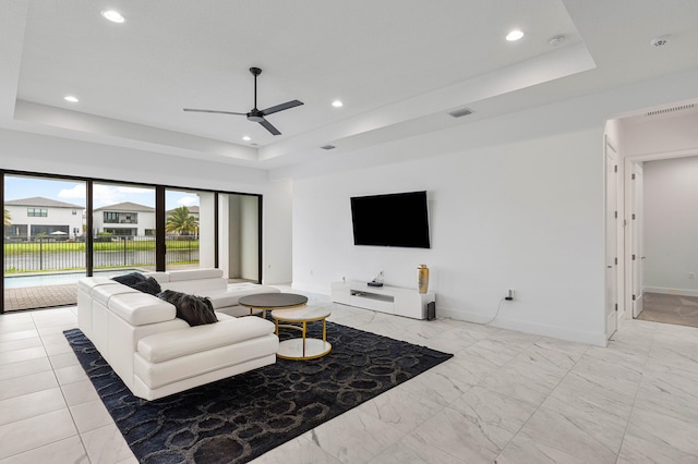 tiled living room featuring ceiling fan and a tray ceiling