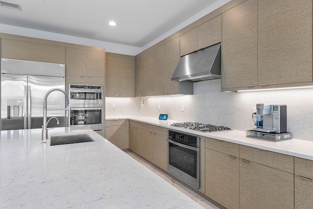 kitchen with appliances with stainless steel finishes, sink, wall chimney exhaust hood, and decorative backsplash