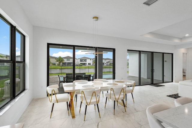 dining space with ceiling fan, light tile patterned flooring, and a tray ceiling