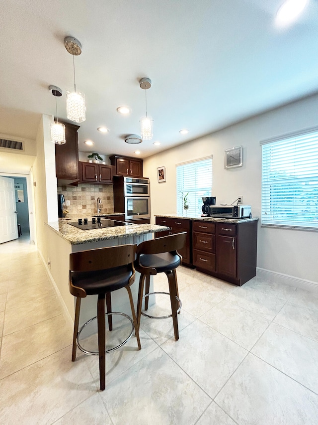 kitchen featuring tasteful backsplash, hanging light fixtures, and light tile patterned floors