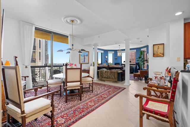 dining area with ornate columns, tile patterned flooring, a wall of windows, and an inviting chandelier