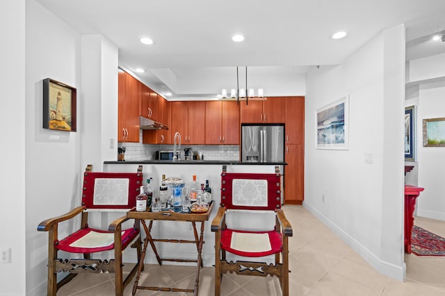 kitchen featuring light tile patterned flooring, backsplash, stainless steel fridge, and hanging light fixtures