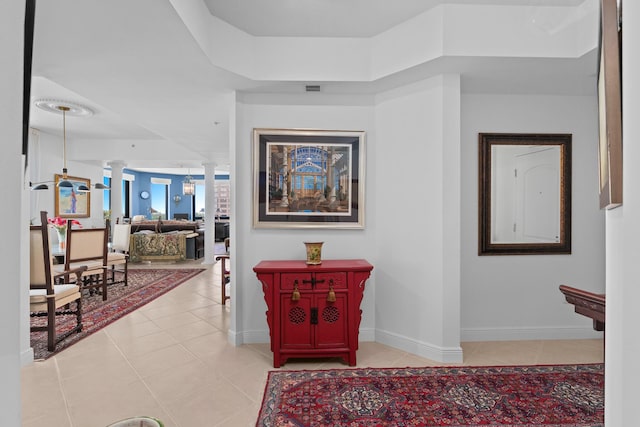 hall with ornate columns, baseboards, light tile patterned floors, and visible vents