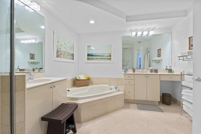 bathroom featuring tile patterned flooring, tiled tub, and vanity