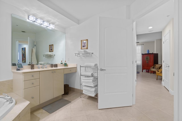 bathroom featuring tile patterned flooring, baseboards, a bath, and vanity