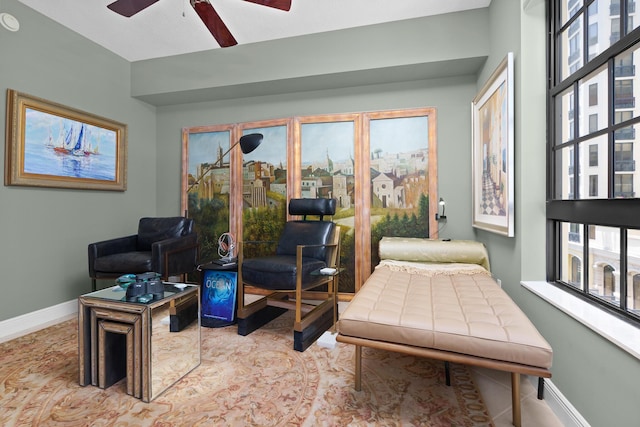 sitting room with a ceiling fan and baseboards