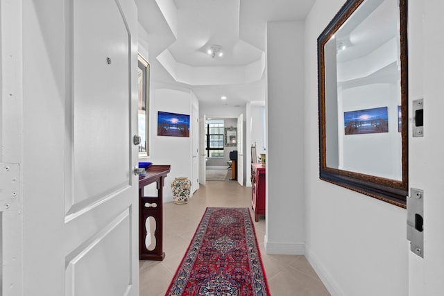 corridor featuring light tile patterned flooring and baseboards