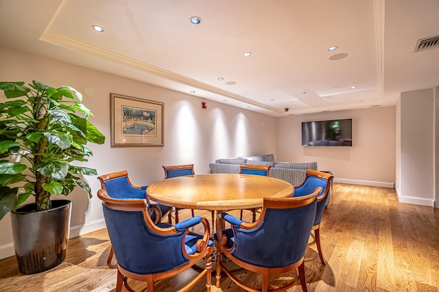 dining area featuring light wood-type flooring and a raised ceiling