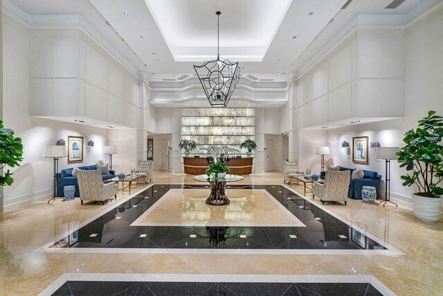 interior space with a towering ceiling, white cabinets, a raised ceiling, and light stone counters