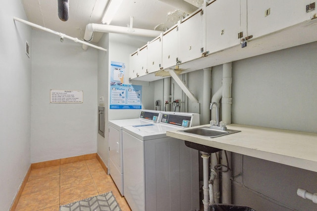 clothes washing area with light tile patterned flooring, sink, independent washer and dryer, and cabinets