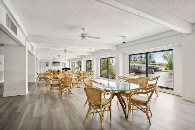 dining area featuring a textured ceiling, ceiling fan, beamed ceiling, and wood-type flooring