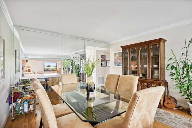 dining space with light hardwood / wood-style floors and crown molding