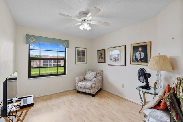 sitting room featuring a textured ceiling, ceiling fan, and light wood-type flooring