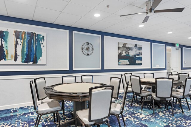 carpeted dining room featuring ceiling fan and a drop ceiling