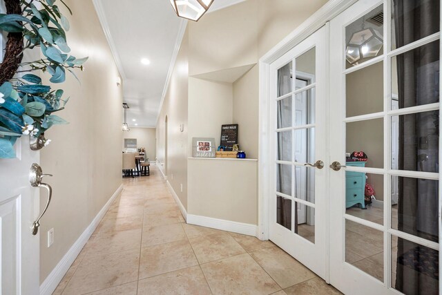 hallway with french doors, crown molding, and light tile patterned floors