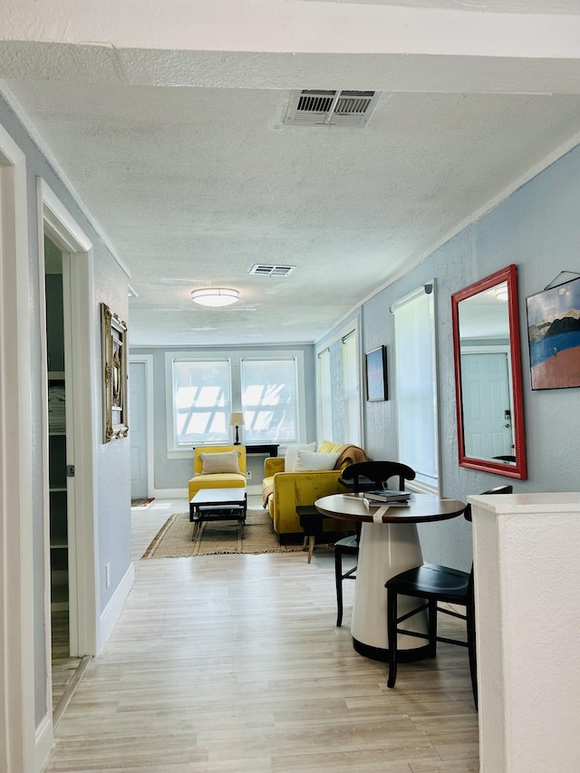 hallway with a textured ceiling and light wood-type flooring