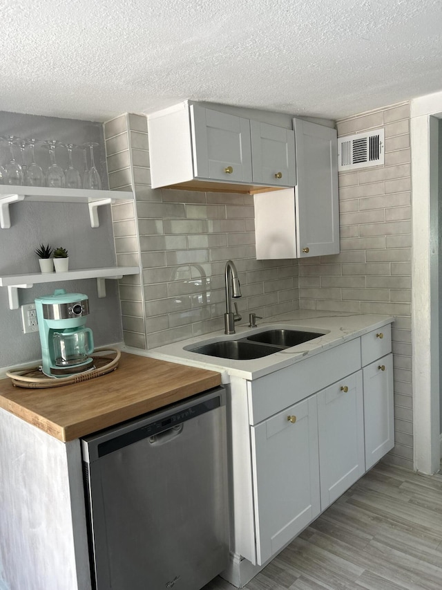 kitchen featuring dishwasher, wood counters, white cabinets, sink, and light wood-type flooring