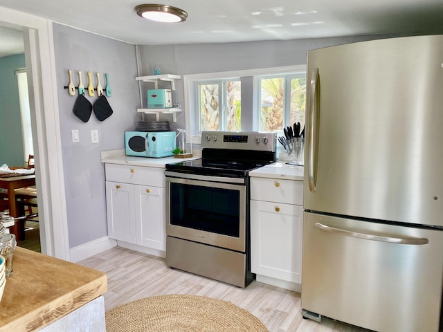 kitchen with light wood-type flooring, stainless steel appliances, and white cabinetry