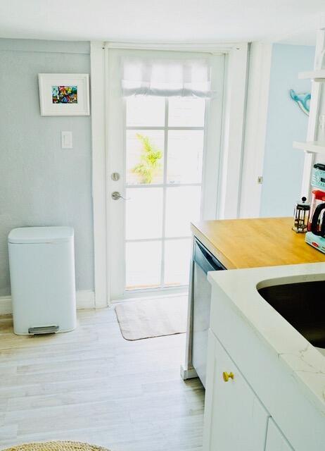 kitchen featuring white cabinets, dishwasher, and light hardwood / wood-style flooring