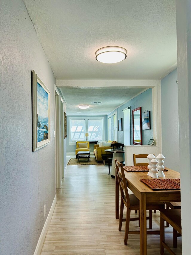 dining room featuring light hardwood / wood-style flooring and a textured ceiling