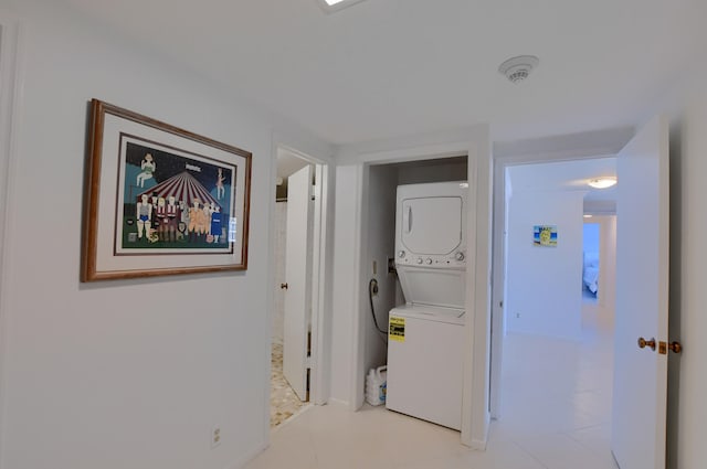 hallway featuring stacked washer / drying machine and light tile patterned floors