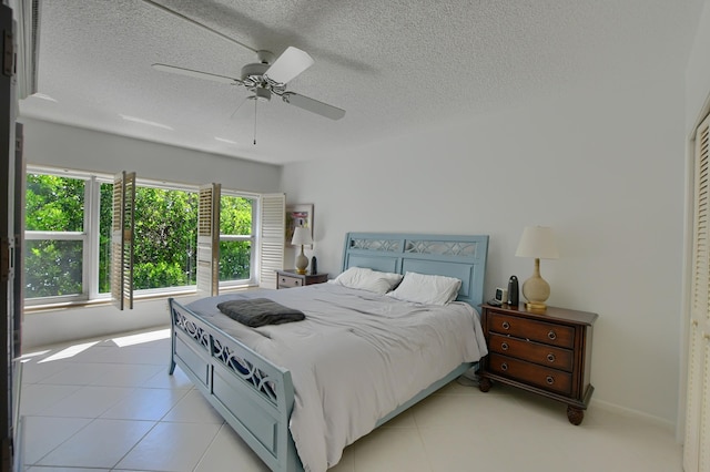 bedroom with ceiling fan, light tile patterned floors, and a textured ceiling