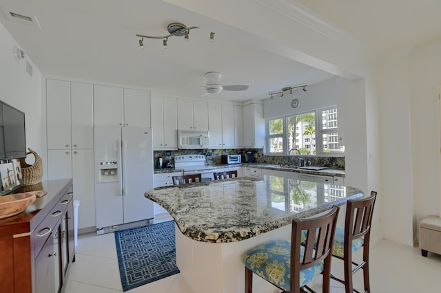 kitchen featuring white appliances, white cabinets, track lighting, and tasteful backsplash