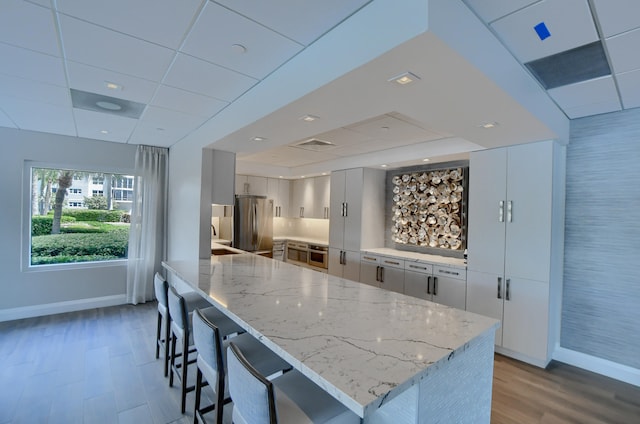 kitchen featuring sink, a paneled ceiling, light hardwood / wood-style flooring, a kitchen island, and stainless steel appliances