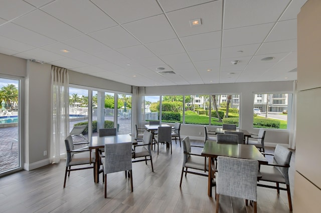 dining room with a drop ceiling and light wood-type flooring