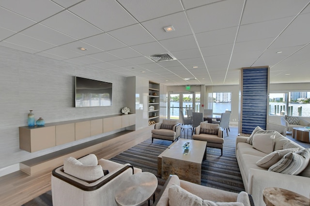 living room featuring a drop ceiling, wood-type flooring, and built in features