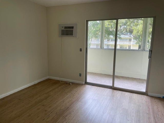 unfurnished room with a wall unit AC and hardwood / wood-style floors