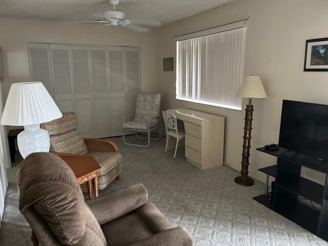 carpeted living room with ceiling fan