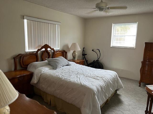 carpeted bedroom with a textured ceiling and ceiling fan