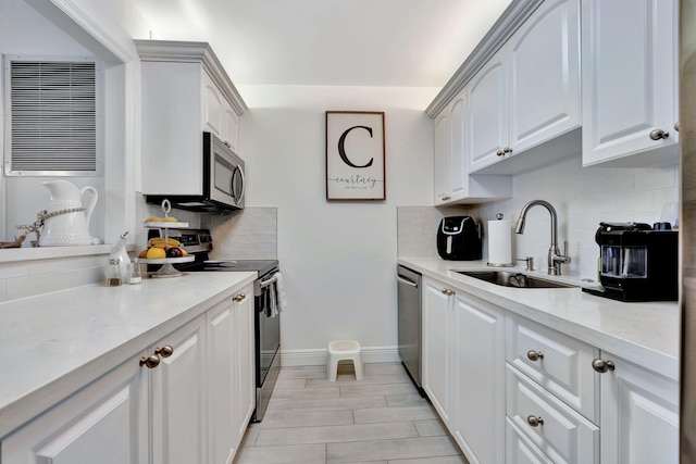 kitchen with backsplash, white cabinets, sink, appliances with stainless steel finishes, and light stone counters