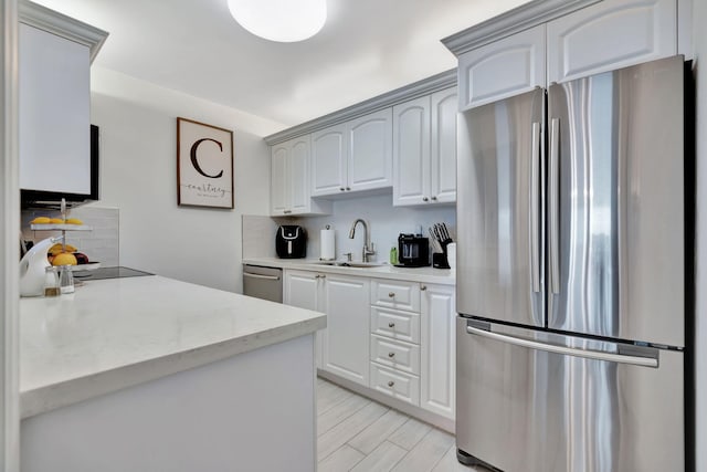 kitchen with backsplash, white cabinetry, sink, and stainless steel appliances