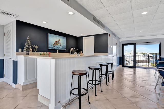 bar featuring a drop ceiling and white cabinets