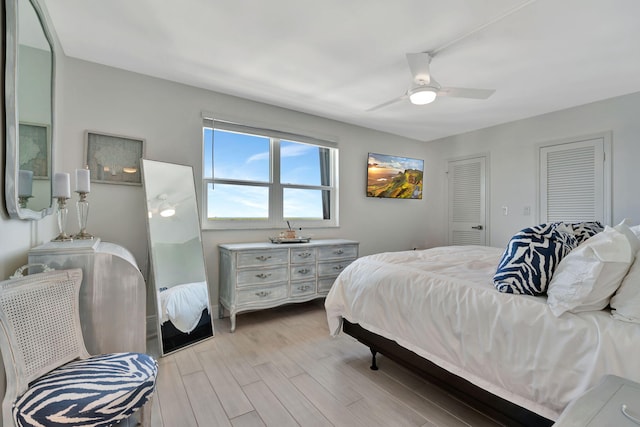 bedroom featuring multiple closets, ceiling fan, and light hardwood / wood-style flooring