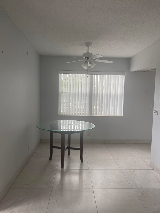 tiled dining space with a textured ceiling and ceiling fan