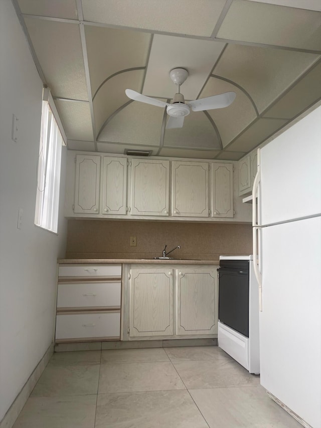 kitchen featuring sink, a drop ceiling, white appliances, ceiling fan, and light tile patterned flooring