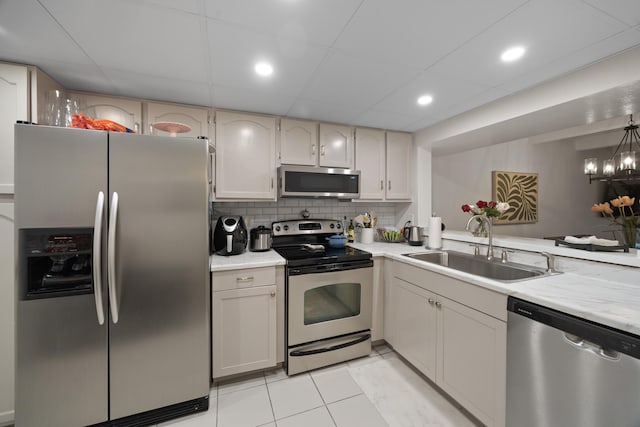 kitchen with sink, appliances with stainless steel finishes, decorative backsplash, light tile patterned floors, and pendant lighting