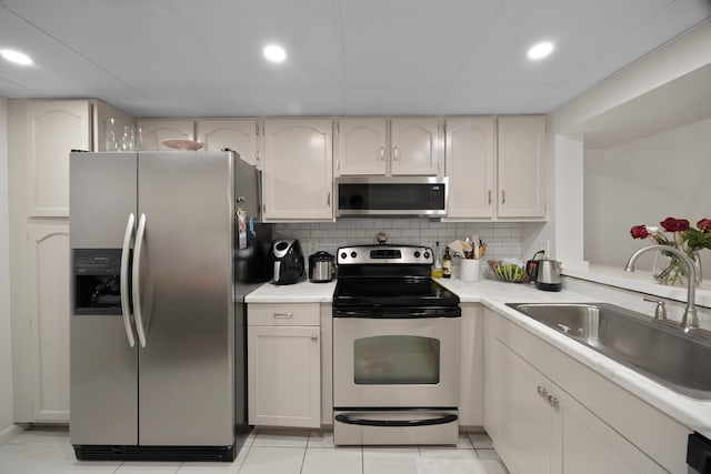 kitchen with decorative backsplash, white cabinets, appliances with stainless steel finishes, sink, and light tile patterned flooring