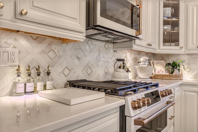 kitchen with backsplash, high end white range, and white cabinetry