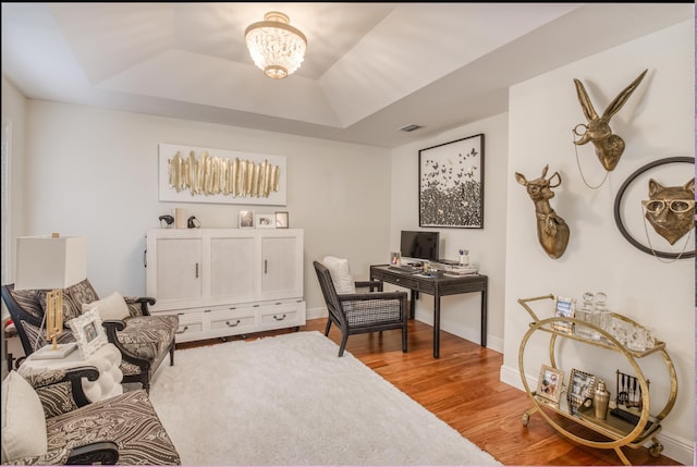 office featuring hardwood / wood-style floors, a tray ceiling, and an inviting chandelier