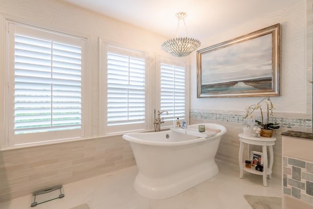 bathroom featuring a bathing tub, a notable chandelier, and tile walls