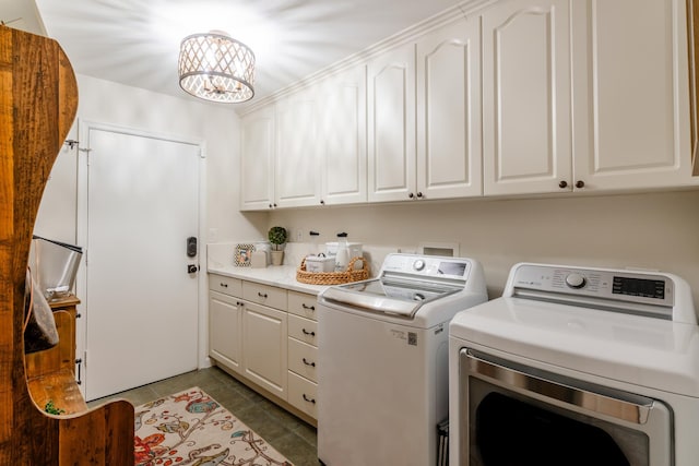 laundry area with dark tile patterned flooring, cabinets, independent washer and dryer, and an inviting chandelier