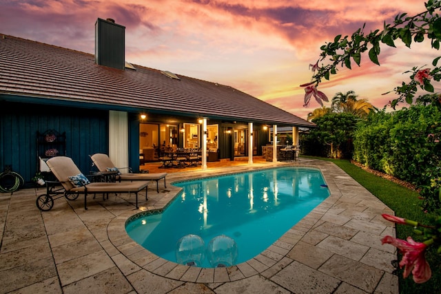 pool at dusk featuring a patio