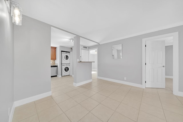 tiled spare room with stacked washing maching and dryer and ornamental molding