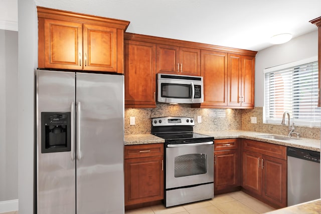 kitchen featuring sink, light stone countertops, tasteful backsplash, light tile patterned floors, and stainless steel appliances